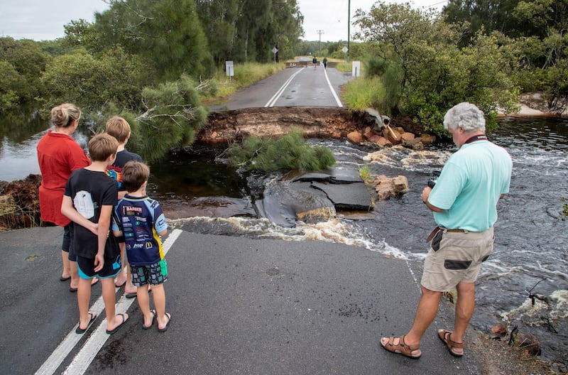 People stand at a washed out section of road at Port Stephens, 200 kilometres north of Sydney. AP