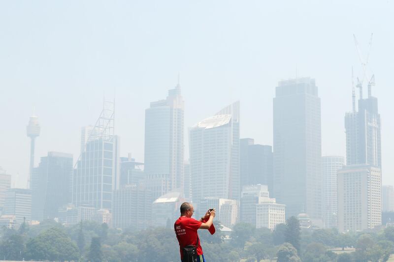 A man takes a picture at Mrs. Macquarie's Chair in front of a smoke covered Sydney skyline on November 19, 2019. Getty Images