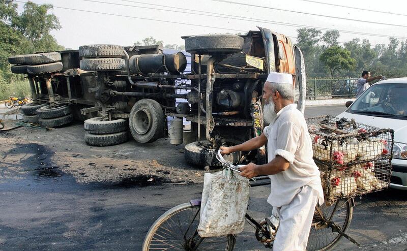 An Indian chicken vendor passes by an overturned container truck on a national highway near Mayur Vihar in New Delhi, 19 September 2007.  Major accidents are common in India due to bad roads, overloaded and ill-maintained vehicles and careless driving. The Delhi-based Institute of Road Traffic Education of India says the country accounts for nearly 10 percent of fatal accidents worldwide.            AFP PHOTO/ Prakash SINGH / AFP PHOTO / PRAKASH SINGH
