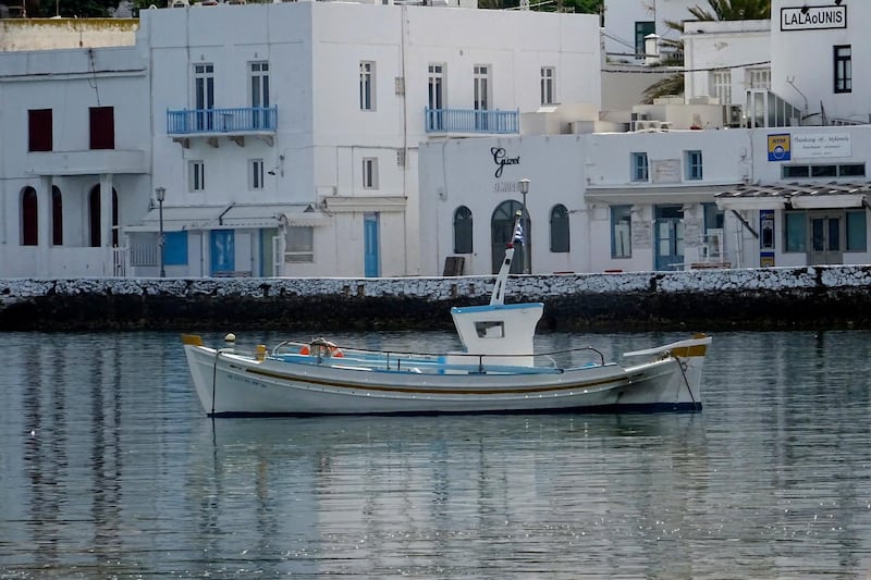 A fishing boat is anchored in front of the main walkway on the Greek island of Mykonos, Greece.