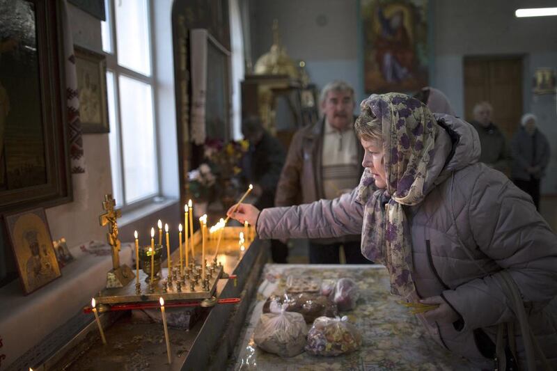 A woman lights a candle before a service in the St Olga and St Vladimir Cathedral in Simferopol, Crimea.The property has come under threat from Crimea’s pro-Moscow leaders, who have hiked up the rent and are threatening to take the property from the church. Alexander Zemlianichenko / AP Photo