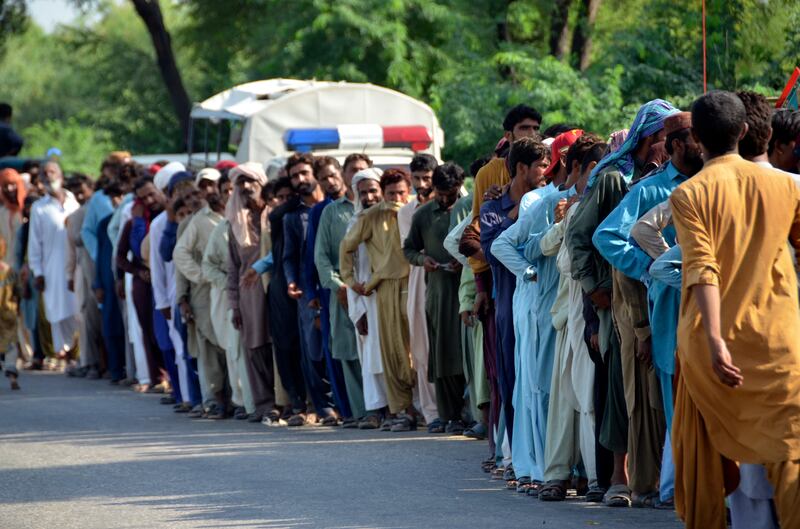 Displaced families queue for relief aid in Jaffarabad. AP