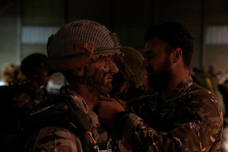 A British paratrooper with the UK's 16th Air Assault Brigade is helped by another soldier before boarding a C130 transport aircraft at RAF Akrotiri air base in Cyprus for an airdrop over Jordan. Britain's armed forces minister says the country's paratroopers are training with Jordanian soldiers to underscore the UK's support for Jordan and regional stability. AP