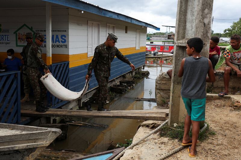 Brazilian soldiers carry a pirarucu seized on a boat. Reuters