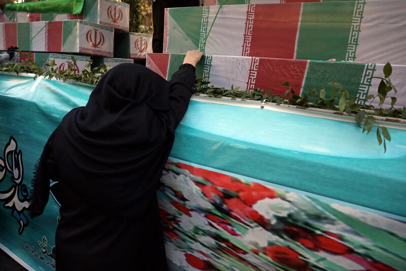 A woman with the flag-draped caskets of unknown soldiers who were killed during the 1980-1988 Iran-Iraq war. AP Photo