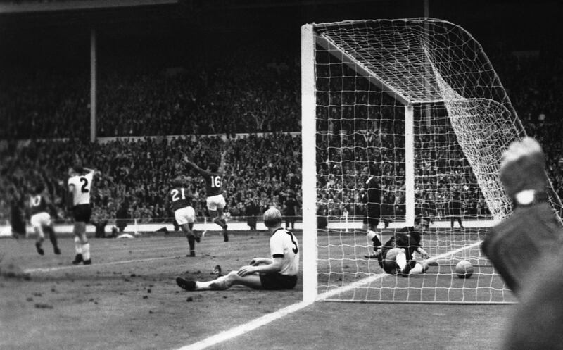 England’s Martin Peters (No. 16) throws out his arms and leaps into the air as he scores England’s second goal while Hunt (No. 21) of England runs over to congratulate him at Wembley, London, United Kingdom on July 30, 1966. Sitting by the goalpost a little dejected is Karl Heinz Schnellinger, the West German full-back while the West German goalkeeper Hans Tilkowski reaches for the ball in the net. (AP Photo/Bippa)