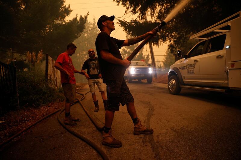 Dave Broome, who is among a group of friends who call themselves “Rescue One”, douses water on a structure during the CZU Lightning Complex Fire on the outskirts of Santa Cruz. Reuters