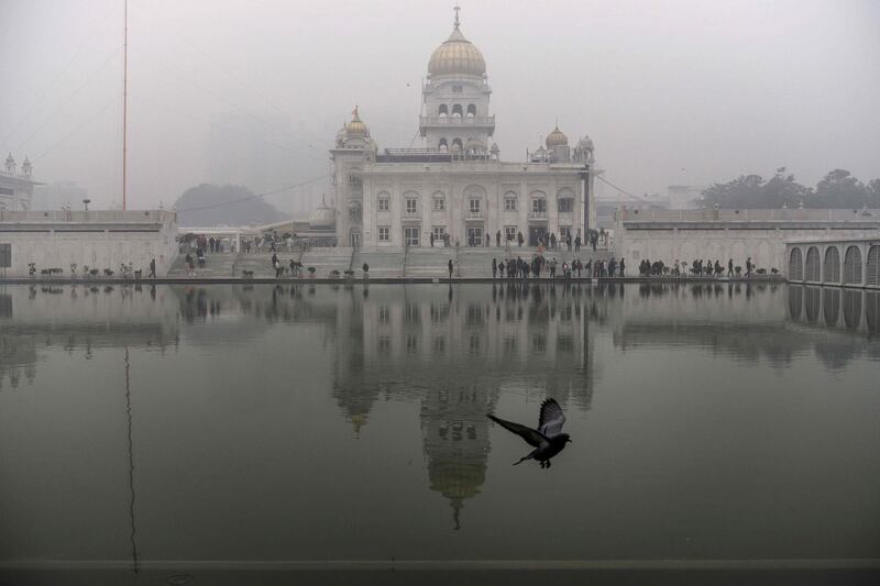 A pigeon flies at the Gurudwara Bangla Sahib under heavy foggy conditions in New Delhi on December 30, 2019. / AFP / Xavier GALIANA
