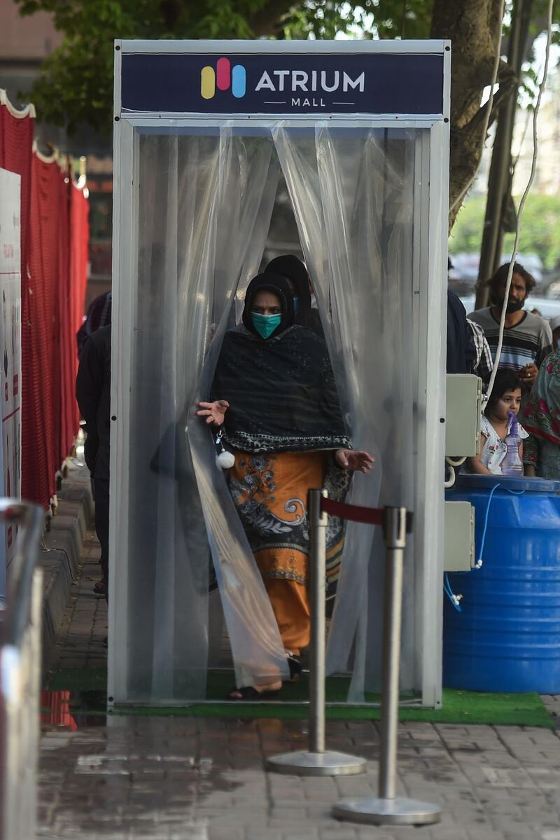 A woman walks through a disinfecting gate before entering a mall ahead of the Muslim Eid al-Fitr festival after the government eased a nationwide lockdown imposed as a preventive measure against the COVID-19 coronavirus in Karachi.   AFP