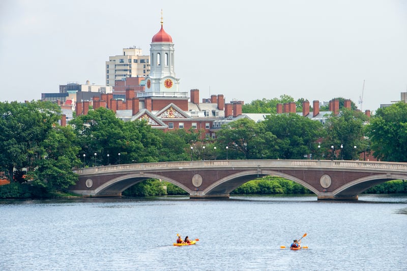 Kayaks at the John W Weeks Bridge and clock tower over Charles River in Harvard University's campus in Boston, Massachusetts. Getty