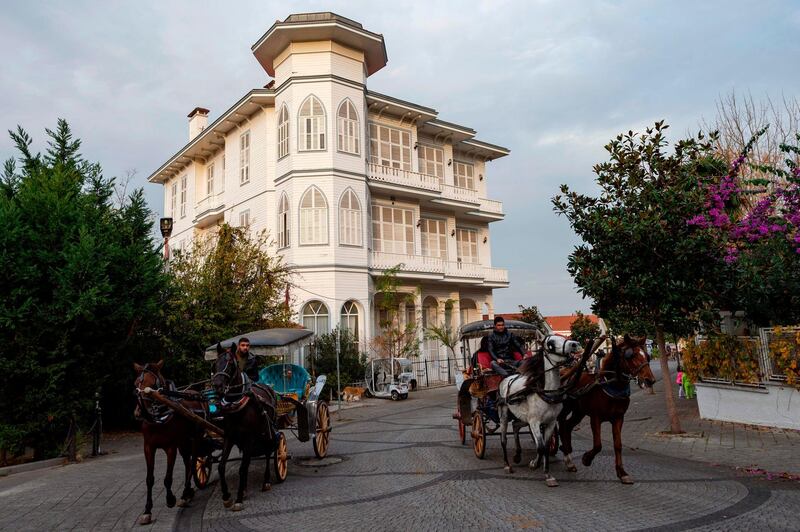 Horse carriages pass by a historic mansion in a street on the island of Buyukada off Istanbul. AFP