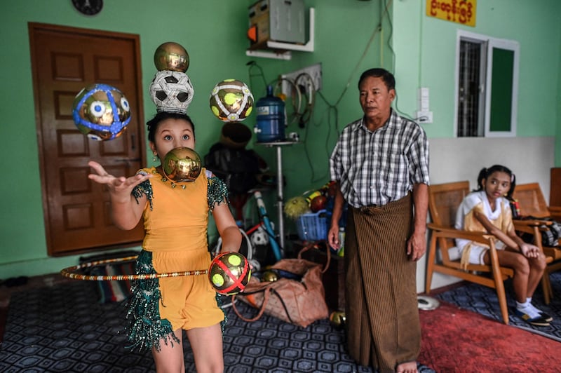 Septuagenarian Ohn Myint watches a performing youth as his granddaughter Han Myint Mo, right, looks on during a juggling training session in Yangon, keeping up a Myanmar juggling tradition on the edge of extinction. AFP