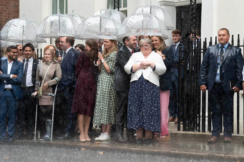 New Health Secretary Therese Coffey and Number 10 staff shelter from a downpour as they wait for Ms Truss to arrive in Downing Street. PA