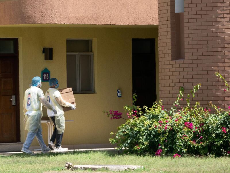 Two members of Red Crescent deliver meals for isolated people following the coronavirus disease (COVID-19) outbreak at Khairan Resort, used as a quarantine centre, in Khairan, Kuwait. Reuters