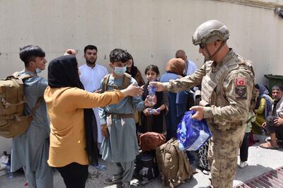 A Turkish soldier offers water to Turkish nationals waiting to board a Turkish Air Force plane at Kabul airport, Afghanistan.