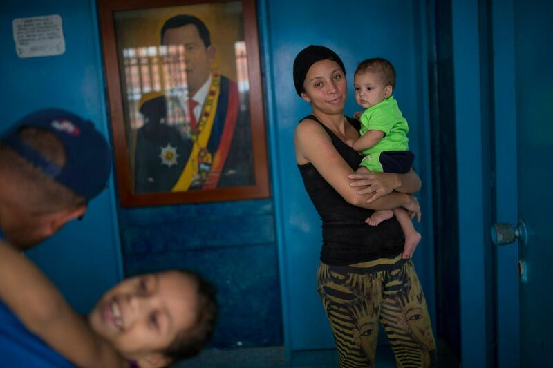 A family plays in the living room of their home, adorned with a portrait of Venezuela's late President Hugo Chavez, in Caracas, Venezuela. AP Photo