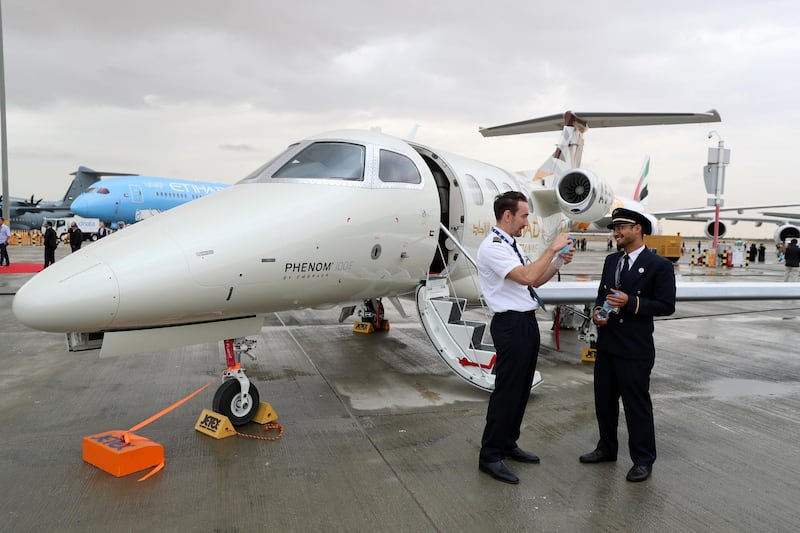 Dubai, United Arab Emirates - November 20, 2019: Two pilots have a chat in front of a Phenom 100 at the Dubai airshow. Wednesday, November 20th, 2017 at Dubai Airshow, Dubai. Chris Whiteoak / The National