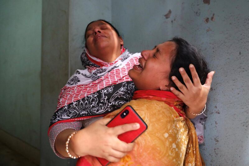 Unidentified relatives of victims mourn near the site of a burnt warehouse in Dhaka, Bangladesh. Reuters