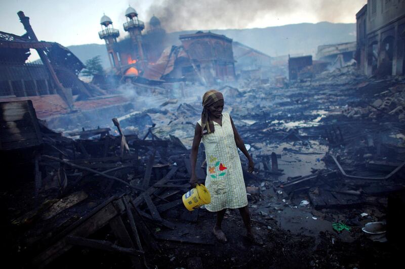 A woman walks near a fire at the Hyppolite iron market in Port-au-Prince, Haiti, January 29, 2010. Picture taken January 29, 2010. REUTERS/Jorge Silva/File Photo  SEARCH "POY DECADE" FOR THIS STORY. SEARCH "REUTERS POY" FOR ALL BEST OF 2019 PACKAGES. TPX IMAGES OF THE DAY.