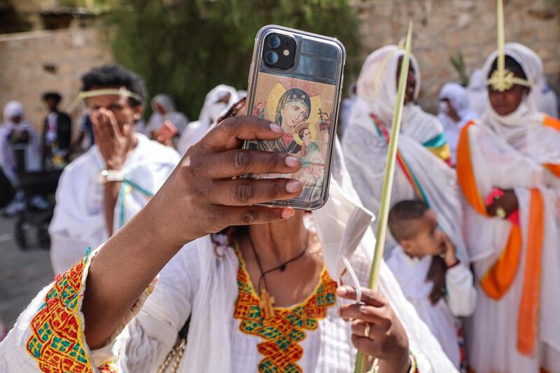 An Ethiopian Orthodox Christian uses her phone, which bears the image of the Virgin Mary with Jesus, to film proceedings during Palm Sunday celebrations outside the Church of the Holy Sepulchre in Jerusalem. AFP