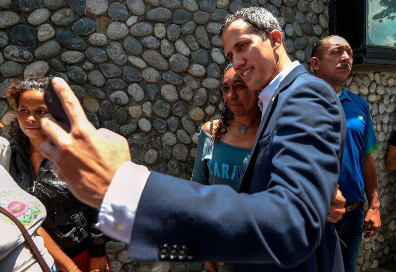 Venezuelan opposition leader and self-proclaimed interim president Juan Guaido (R) makes a selfie with a supporter after a press conference in Caracas, on March 21, 2019, following tha arrest of his chief of staff Roberto Marrero.  President Nicolas Maduro's regime in Venezuela Thursday defied US warnings to leave the opposition alone by arresting in a predawn raid the chief of staff to Juan Guaido, recognized by Washington as the country's interim leader. Guaido and the opposition-ruled congress said on Twitter that Roberto Marrero was grabbed by SEBIN intelligence agency officers in his Caracas home and taken to an "unknown" location. / AFP / Juan BARRETO
