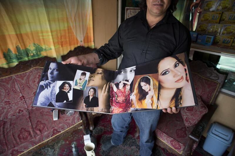 A wedding photographer proudly shows his bridal portraits at his photo studio.