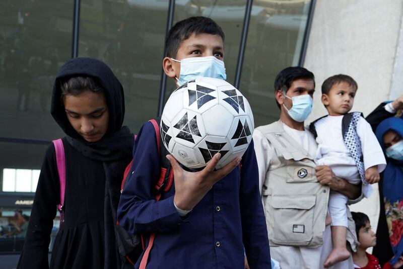 A boy holds a football as he and other Afghan refugees board a bus taking them to a processing centre upon arrival at Dulles International Airport on Friday. Reuters