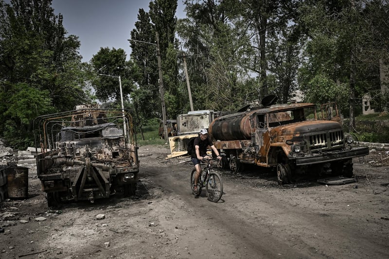 A man passes two destroyed military lorries in Lysychansk. AFP