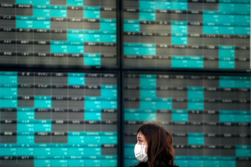 In this Thursday, March 12, 2020, photo, a woman stands in front of an electronic stock board showing Japan's Nikkei 225 index at a securities firm in Tokyo. Asian stock markets and U.S. futures fell Monday, March 16, 2020, after the Federal Reserve slashed its key interest rate to shore up economic growth in the face of mounting global anti-virus controls that are shutting down business and travel. (AP Photo/Eugene Hoshiko)