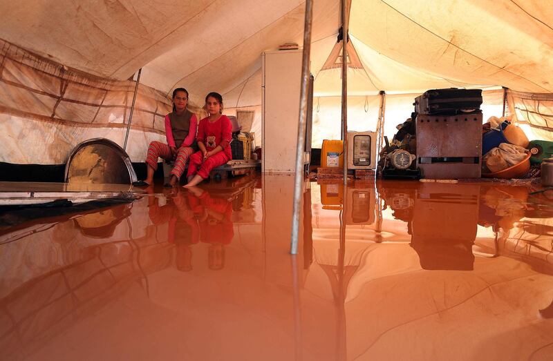 Two girls sit inside a flooded tent at the flooded Mukhayyam Al Khair camp near the village of Kafr Uruq in the north of Idlib province on December 17, 2020. AFP