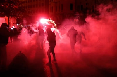 Anti-government protesters are covered by tear gas smoke, as they throw firecrackers against the riot police, during ongoing protests against the political elites in Beirut, Lebanon, Saturday, Jan. 18, 2020. Riot police fired tear gas and sprayed water cannon near parliament in Lebanon's capital Saturday to disperse thousands of protesters after riots broke out during a march against the ruling elite amid a severe economic crisis. (AP Photo/Hussein Malla)
