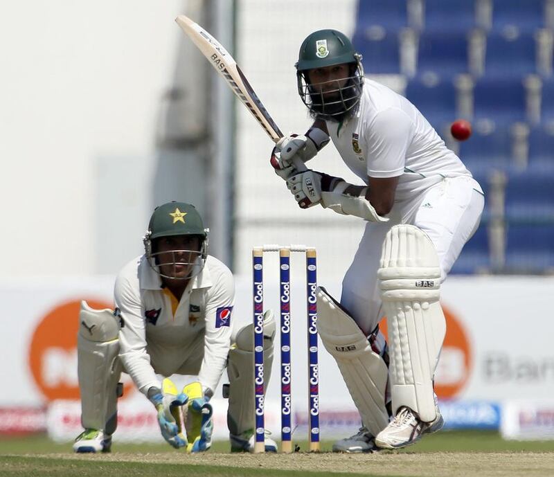 Hasim Amla, right, of South Africa bats as Pakistan's wicketkeeper Kamran Akmal watches on during their first Test at the Sheikh Zayed Cricket Stadium in Abu Dhabi on Monday. South Africa's paceman Mohammad Irfan took two early wickets to leave his team at 66-3 at lunch on the opening day of the first Test. Karim Sahib / AFP