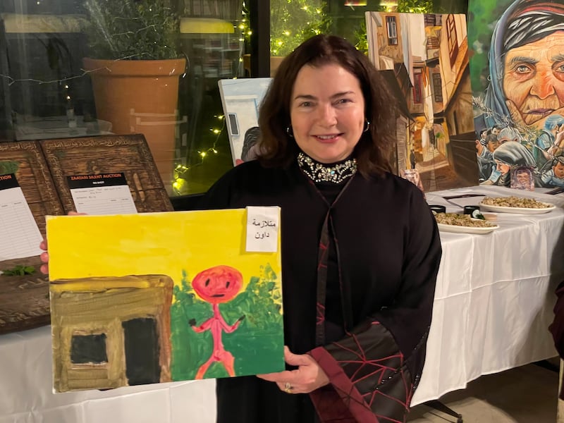 Professor Karen Fisher with a painting by a Syrian refugee who has Down Syndrome and lives at the Zaatari refugee camp 