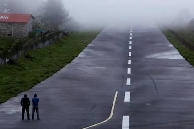 In this Sunday, May 26, 2013 photo, policemen stand on the runway during bad weather conditions at Lukla airport, Nepal. Carved out of side of a mountain, the airport was built by Sir Edmund Hillary in 1965, and at an altitude of 2,843 meters (9,325 feet) it has earned the reputation of being one of the most extreme and dangerous airports in the world. (AP Photo/Niranjan Shrestha) *** Local Caption ***  Nepal Everests Airport.JPEG-0c4be.jpg