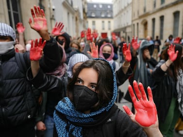 Protesters display mock blood on their hands as they take part in a demonstration in front of the Institute of Political Studies (Sciences Po Paris) occupied by students, in support of Palestinians, in Paris on April 26, 2024.  A few dozen students stay mobilized in support of Palestinians occupying a new building at Sciences Po Paris since April 25, 2024, evening, the day after police evacuated another of the school's sites, in the wake of actions at American universities.  (Photo by Dimitar DILKOFF  /  AFP)