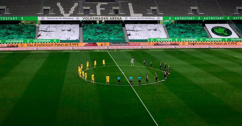 Dortmund and Wolfsburg players observe a minute's silence in homage to the victims of Covid-19 pandemic. AFP