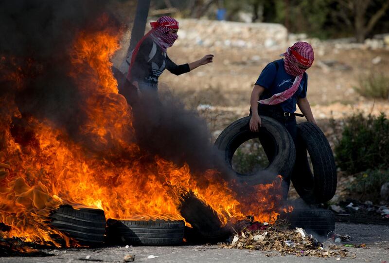 A Palestinian protester carries tires for burning during clashes with Israeli troops during demonstration in against the Israeli offensive on Gaza, at checkpoint Beit El near the West Bank city of Ramallah. AP Photo
