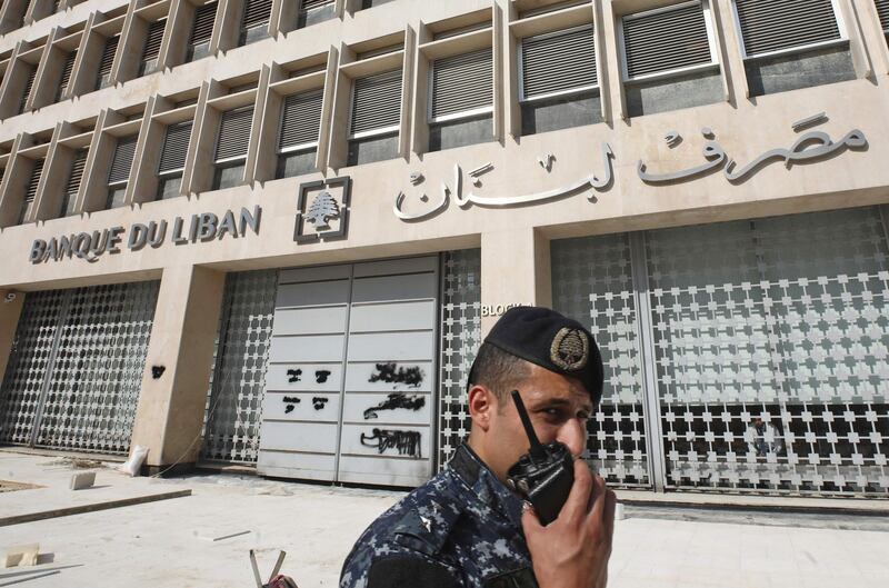A member of the Lebanese security forces stands at the entrance of the Central Bank after anti-government protesters broke down a construction barrier as they rally at the same time of a press conference held by the bank's governor in Beirut on November 11, 2019. Lebanon's central bank on said it would strive to maintain the local currency's peg to the US dollar and ease access to the greenback after weeks of mass protests. / AFP / ANWAR AMRO
