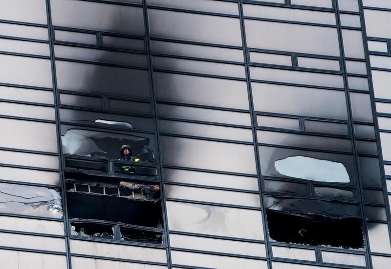 A firefighter looks out from the window of a damaged apartment in Trump Tower in New York on April 7, 2018. The New York Fire Department says the blaze broke out on the 50th floor shortly before 6pm. Craig Ruttle / AP Photo