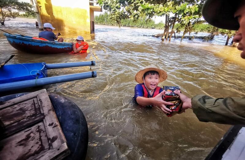 A boy receives donation foods from a volunteer at a flooded area in Quang Binh province, Vietnam. Reuters