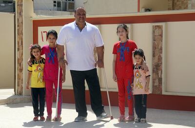 Iraqi paralympic weightlifter Faris al-Ajeeli (C) is pictured with his children in front of his home in the northern city of Mosul on August 25, 2018. - Two years ago, the Islamic State group offered two successful Iraqi weightlifters a choice -- either they compete in the Rio Paralympics, or stay in Mosul, then controlled by the jihadists. But there was a big catch: they were to hoist the group's flag instead of the Iraqi national one, and disobeying IS would have left their families back in Mosul at risk of reprisals. (Photo by Zaid AL-OBEIDI / AFP)