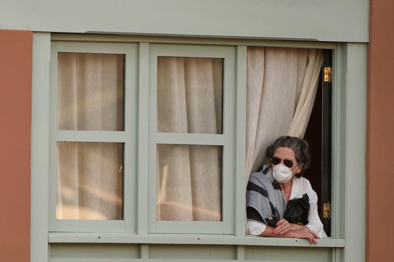 A woman looks out of a window at the H10 Costa Adeje Palace hotel in La Caleta, in the Canary Island of Tenerife, Spain.  AP