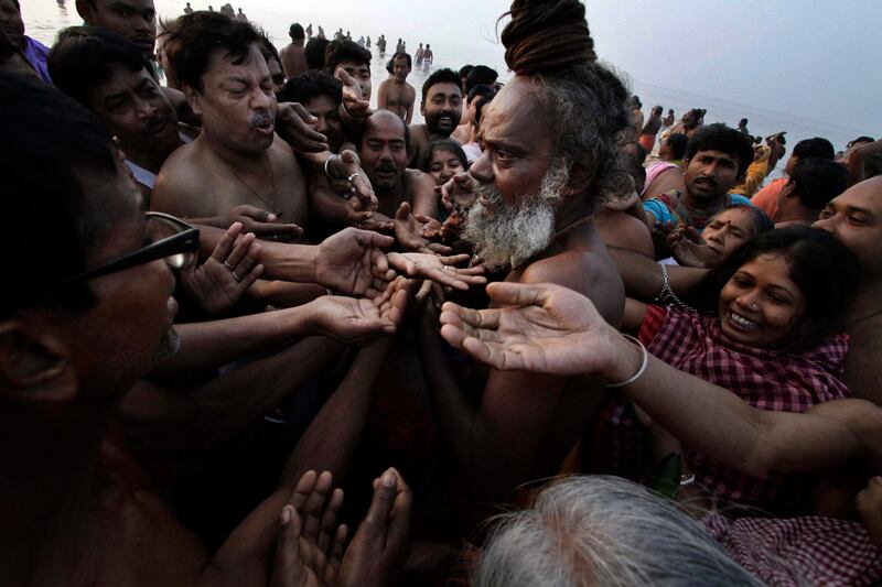 Pilgrims seek blessings from a Hindu holy man at Gangasagar, India, Monday, Jan. 14, 2013. Thousands of Hindu pilgrims bathed at Gangasagar, the confluence of Hindu holy river Ganges and the Bay of Bengal, 140 kilometers (87 miles) south of Kolkata, an act that is expected to help them wash off their sins on the auspicious occasion of Makar Sankranti, as it is called in northern and eastern India. The day marks the beginning of "uttarayana" or the suns northward movement, considered to be very auspicious astrologically. (AP Photo/Bikas Das) *** Local Caption ***  India Hindu Festival.JPEG-0c37f.jpg