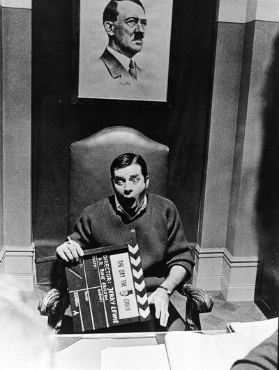 American actor and comedian Jerry Lewis sits open mouthed below a picture of Adolf Hitler and holds a film clapper on the set of the film, The Day The Clown Cried, April 14, 1972. Photo: Express Newspapers/Getty Images