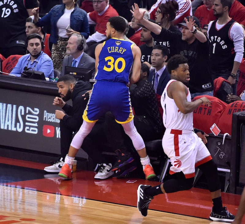 Golden State Warriors guard Stephen Currry, centre, goes out of bounds as rapper Drake, left, moves out of the way. EPA