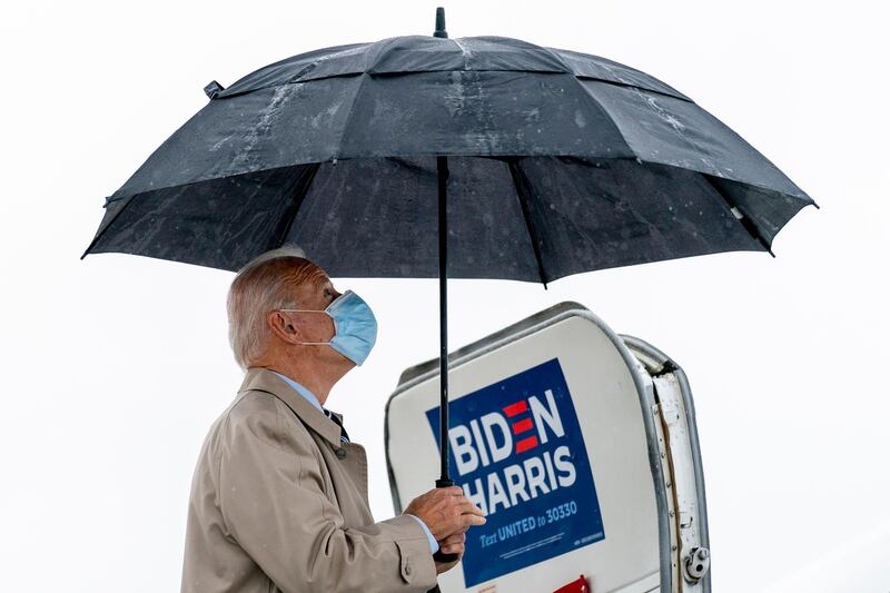 Democratic presidential candidate Joe Biden closes his umbrella as he boards his campaign plane at New Castle Airport in New Castle, Delaware, to travel to Florida for drive-in rallies. AP Photo