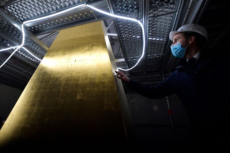 A restorer touches the gold-leafed pyramidal cap of the Obelisk of Luxor, being restored, on the Place de la Concorde in Paris on January 17. AFP