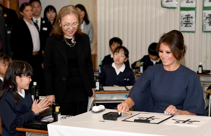 US first lady Melania Trump finishes her calligraphy helped by a schoolgirl, left, as she attends a calligraphy class of the 4th grader at Kyobashi Tsukiji Elementary School in Tokyo. The part of Japanese words reads: "Peace." A standing woman is an interpreter. Toshifumi Kitamura / Pool Photo via AP