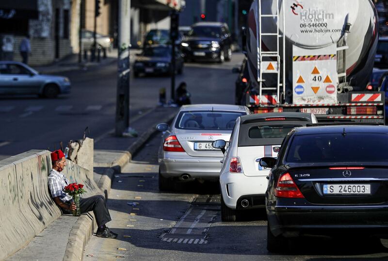 A flower vendor rests along the side of a road by vehicles waiting at a traffic light in Beirut.  AFP