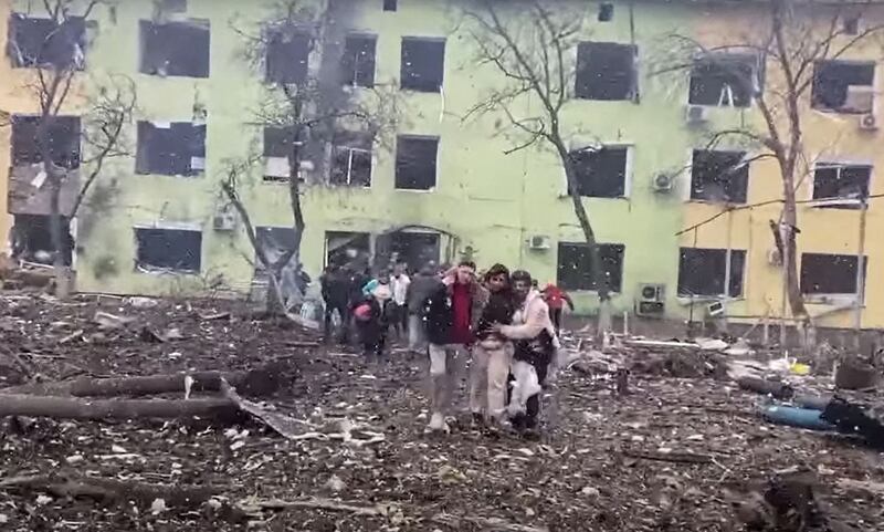 People are helped out of a damaged children's hospital following a Russian air strike in the southeastern city of Mariupol, Ukraine. AFP